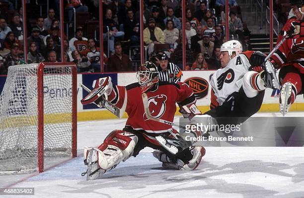 Goalie Mike Dunham of the New Jersey Devils looks to make the save as Rod Brind'Amour of the Philadelphia Flyers flies through the air on April 13,...