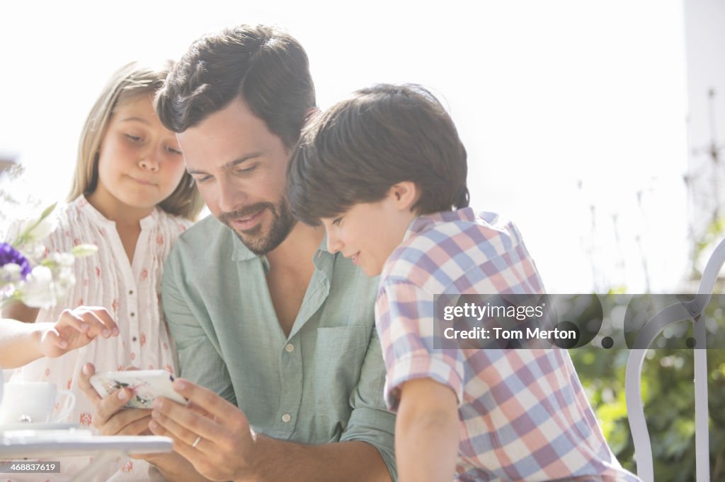 Padres e hijos usando teléfonos móviles al aire libre