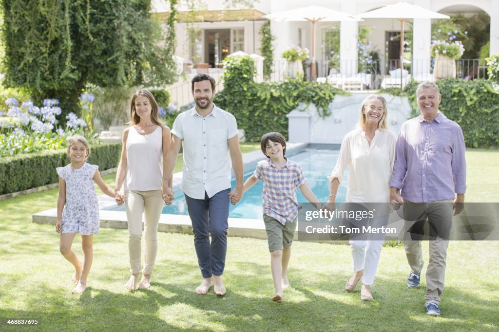 Multi-generation family holding hands and walking in backyard