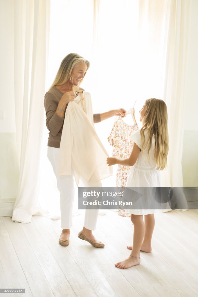 Grandmother and granddaughter holding clothing at window