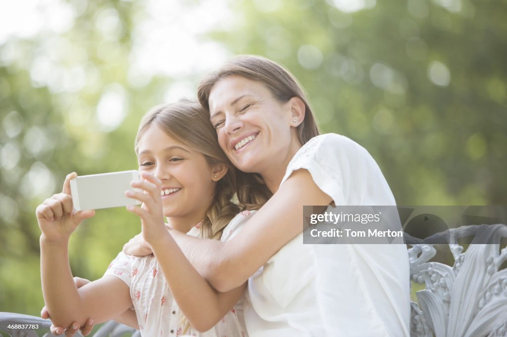 Mother and daughter using cell phone outdoors