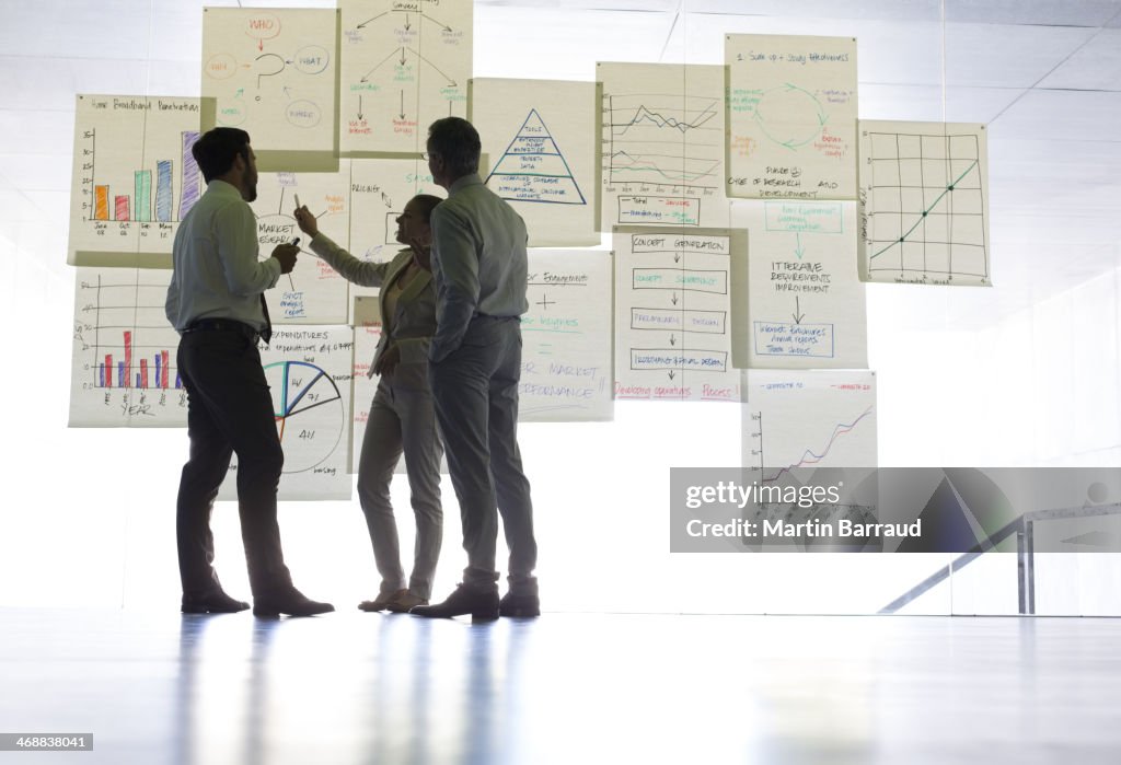 Business people discussing charts and graphs hanging in office