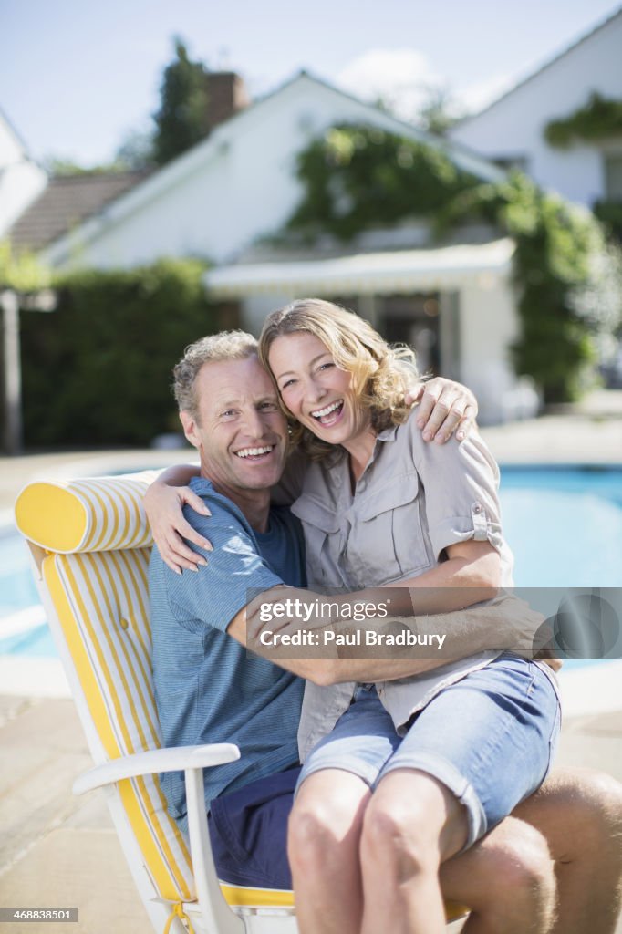 Couple sitting in lounge chair at poolside