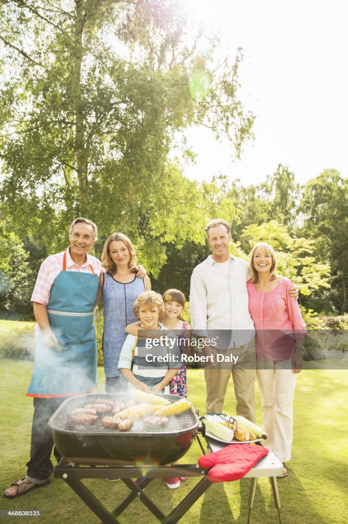 Multi-generation family standing at barbecue in backyard