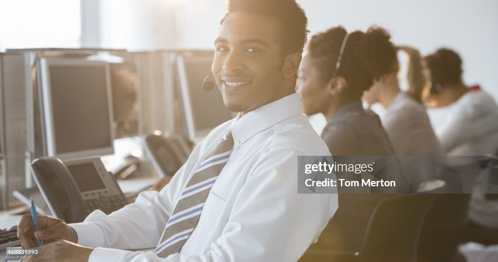 Businessman with headset smiling in office