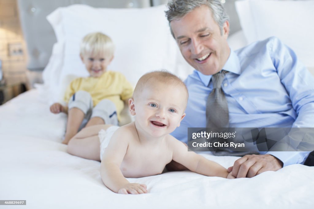 Father and children playing on bed