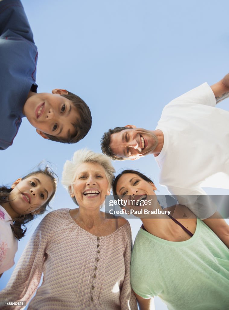 Multi-generation family smiling in huddle against blue sky