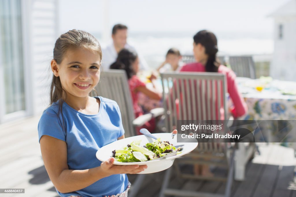 Girl holding salad on sunny patio