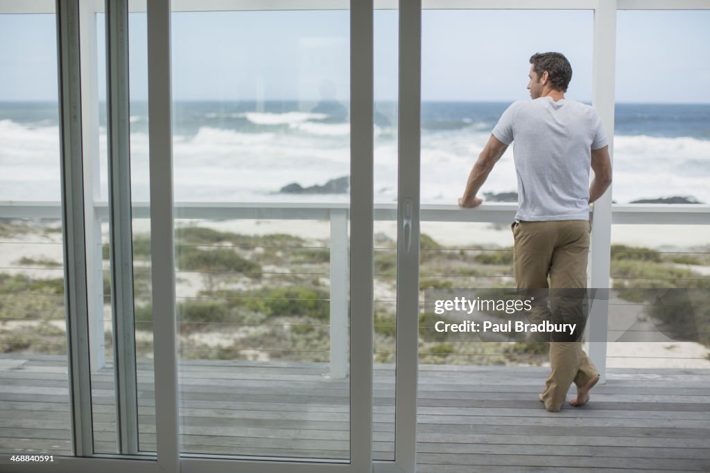 Mann im Blick auf das Meer von der Terrasse