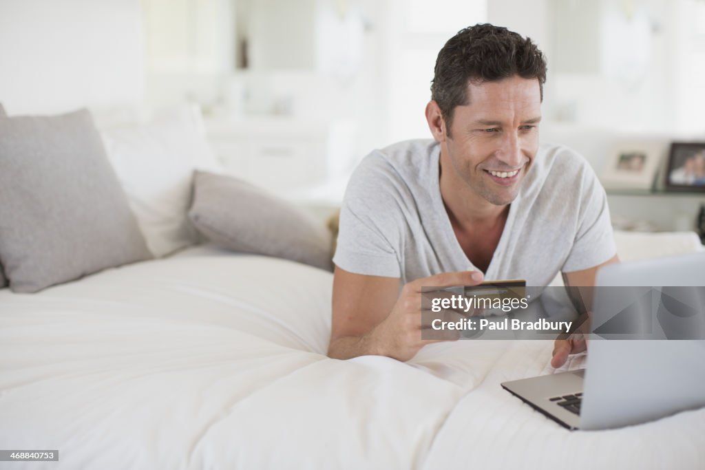 Homem compras online com o laptop na cama