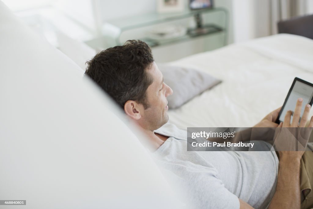 Uomo mediante Tavoletta digitale sul letto