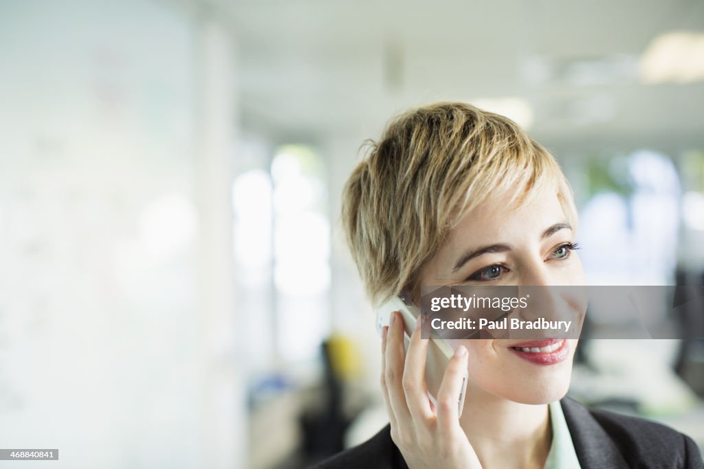 Businesswoman talking on cell phone in office