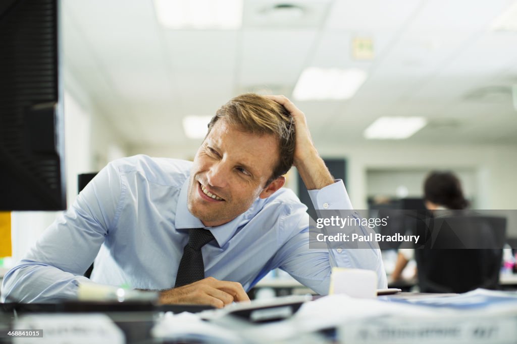 Businessman squinting at desk in office