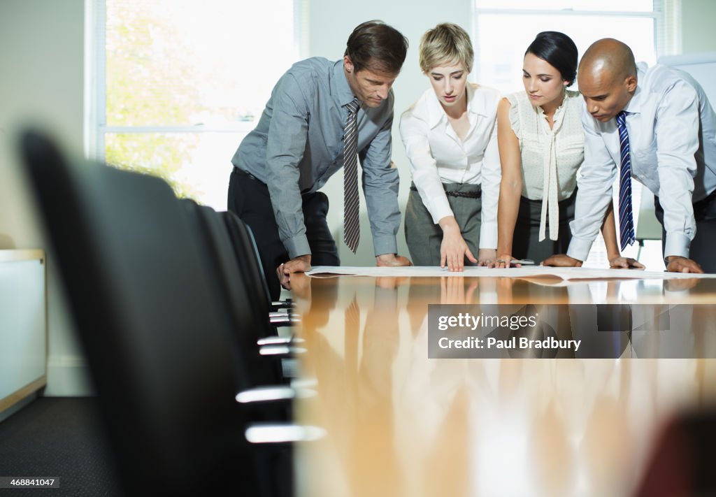 Business people examining blueprints in meeting