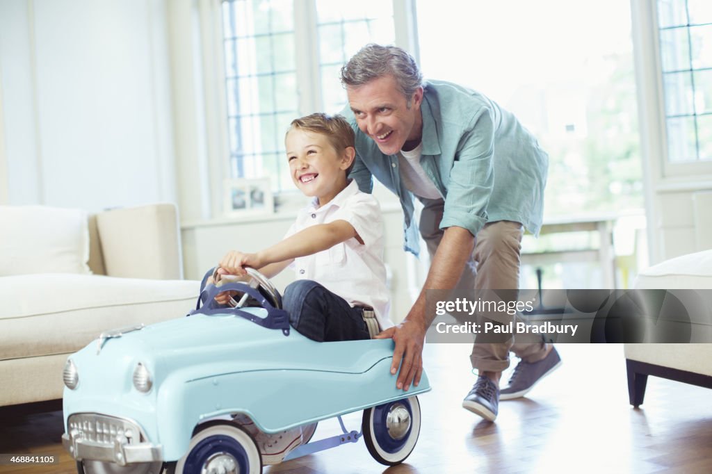 Father pushing son in toy car