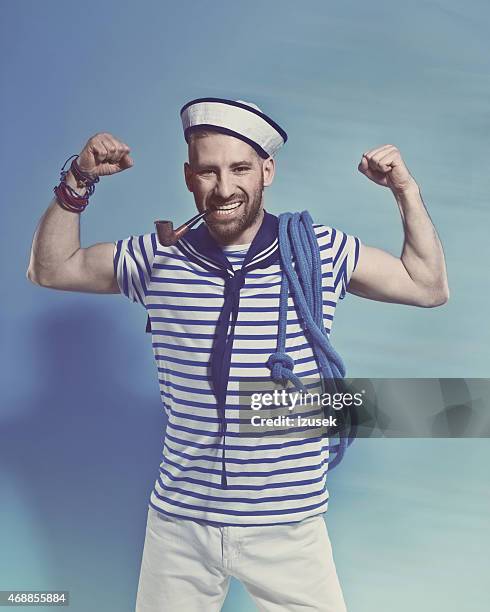 bearded sailor man smoking pipe and flexing his arms - sailor arm stockfoto's en -beelden