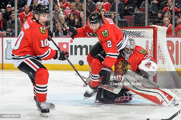 Patrick Sharp and Duncan Keith of the Chicago Blackhawks lunge for the puck next to goalie Corey Crawford during the NHL game against the Minnesota...