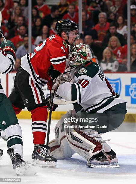 Joakim Nordstrom of the Chicago Blackhawks collides with Devan Dubnyk of the Minnesota Wild at the United Center on April 7, 2015 in Chicago,...