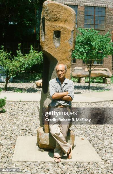 Portrait of the sculptor Isamu Noguchi as he stands in front of one of his works at his museum, Long Island, New York, July 1982.