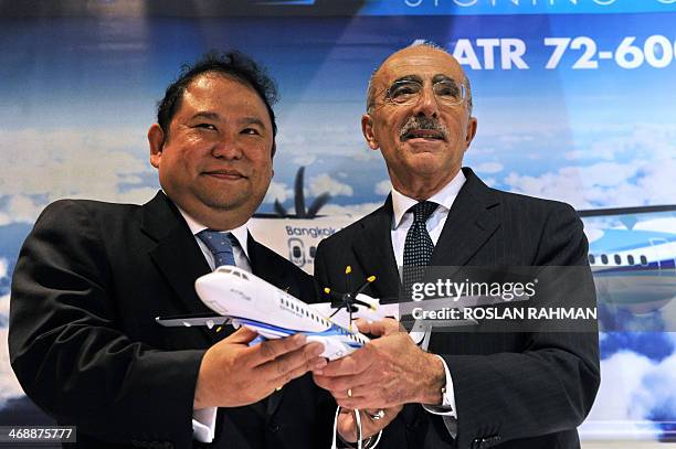 Puttipong Prasarttong-Osoth , President of Bangkok Airways and ATR's Chief Executive Officer Filippo Bagnato , hold a model plane after signing an...