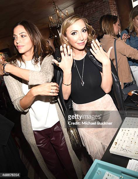 Touriya Haoud and Diana Madison try on Wanderlust + Co jewelry during The Glam App's Glamchella at the Petit Ermitage on April 7, 2015 in Los...