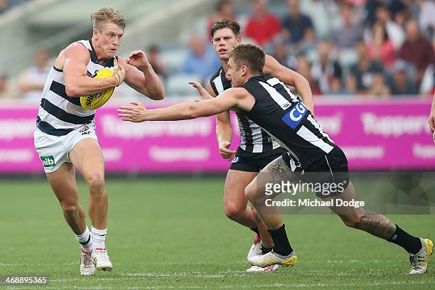 Josh Caddy of the Cats runs with the ball past Dayne Beams of the Magpies during the round one AFL NAB Cup match between the Geelong Cats and the...
