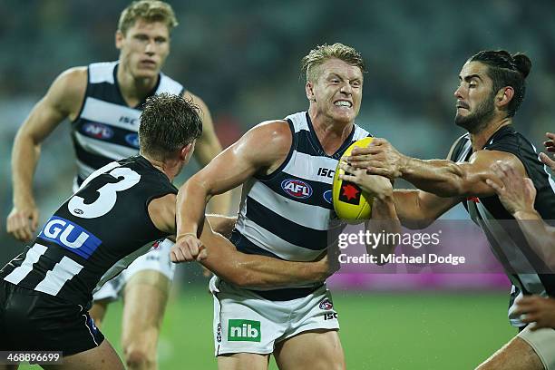 Josh Caddy of the Cats is tackled by Taylor Adams and Brodie Grundy of the Magpies during the round one AFL NAB Cup match between the Geelong Cats...