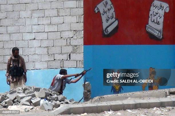 Yemeni fighter opposing the Huthi rebels fires his weapon in the southern Yemeni city of Aden on April 8, 2015 as clashes continue to rage in the...