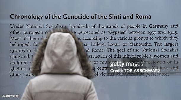 Woman reads an information board at the memorial to the estimated half million Roma and Sinti in Europe murdered by the Nazis during World War II as...