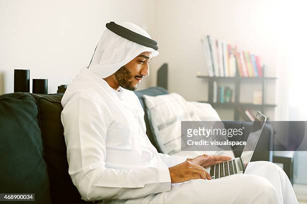 middle eastern man using laptop - emirati laptop stock pictures, royalty-free photos & images