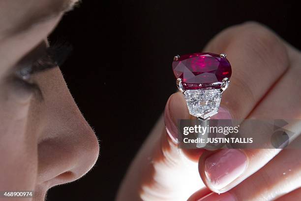 An employee of Sotheby's auction house poses with "The Sunrise Ruby", a rare Burmese ruby weighing 25.59 carats and estimated to sell for $12-18...