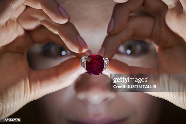 An employee of Sotheby's auction house poses with "The Sunrise Ruby", a rare Burmese ruby weighing 25.59 carats and estimated to sell for $12-18...