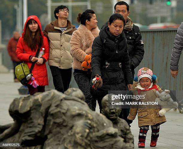 Chinese tourists walk beside a memorial to victims of Japanese war crimes at the Nanjing Massacre Memorial Museum in Nanjing on February 12, 2014....