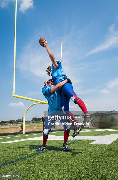 football player jumping to catch ball for touchdown in endzone - touchdown endzone stock pictures, royalty-free photos & images