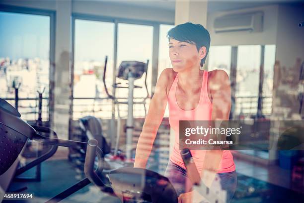 woman on exercise bike in a rooftop gym - buenos aires rooftop stock pictures, royalty-free photos & images