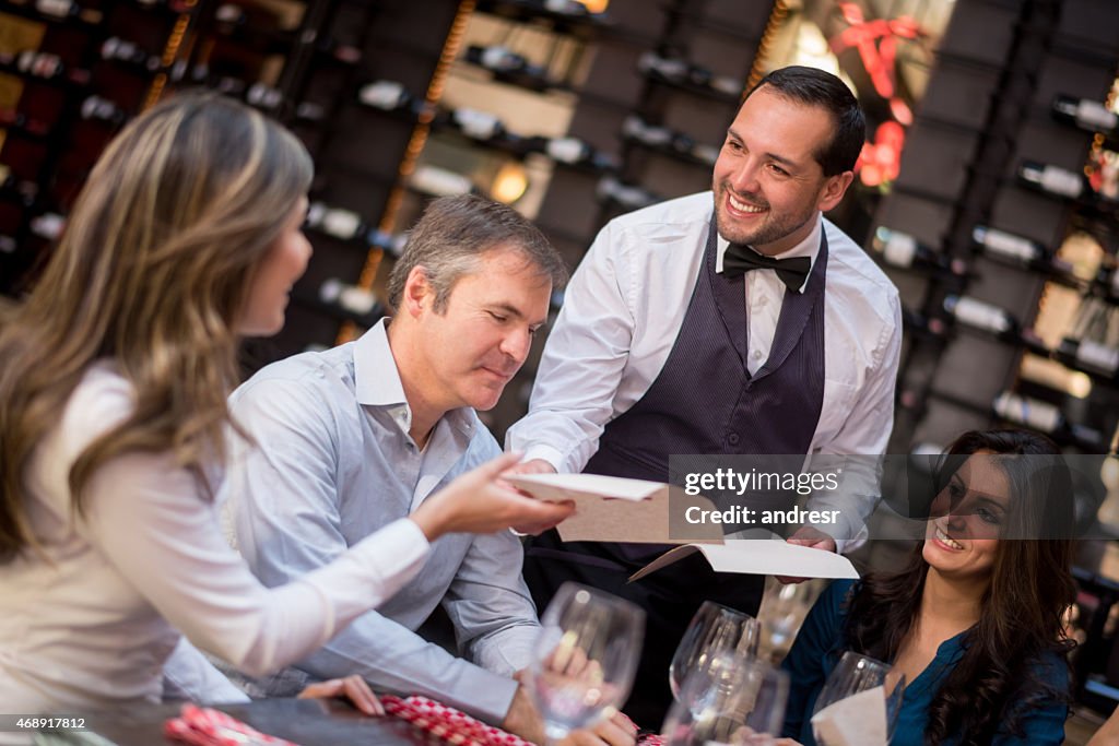 Waiter passing menus to customers at a restaurant