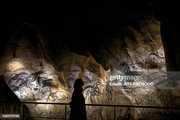 Woman walks past the full-scale reproduction of frescos found at the cave of Pont-D'Arc also known as the Chauvet cave, on April 8, 2015 in Vallon...