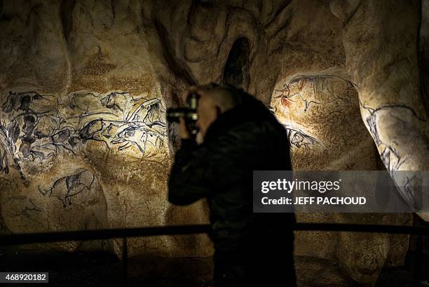 Man takes a photo detail of the full-scale reproduction of frescos found at the cave of Pont-D'Arc also known as the Chauvet cave, on April 8, 2015...