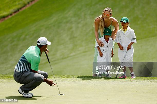 Tiger Woods of the United States waits a green as his girlfriend Lindsey Vonn, son Charlie and daughter Sam look on during the Par 3 Contest prior to...