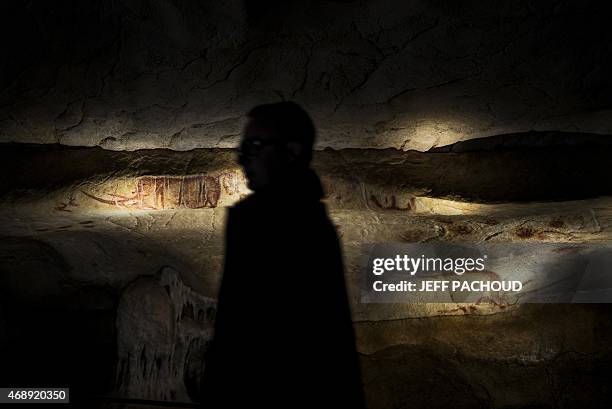 Man walks past the full-scale reproduction of frescos found at the cave of Pont-D'Arc also known as the Chauvet cave, on April 8, 2015 in Vallon Pont...