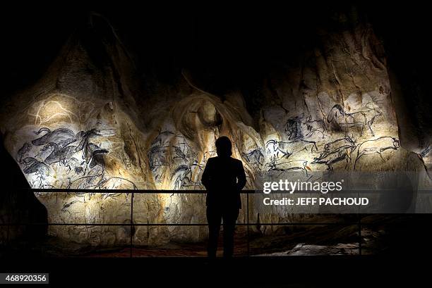 Person looks at the full-scale reproduction of frescos found at the cave of Pont-D'Arc also known as the Chauvet cave, on April 8, 2015 in Vallon...