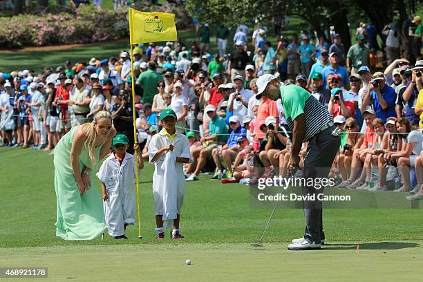 Tiger Woods of the United States hits a putt as his girlfriend Lindsey Vonn, son Charlie and daughter Sam look on during the Par 3 Contest prior to...