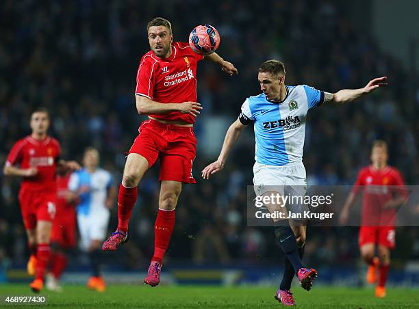 Rickie Lambert of Liverpool jumps with Matthew Kilgallon of Blackburn Rovers during the FA Cup Quarter Final Replay match between Blackburn Rovers...