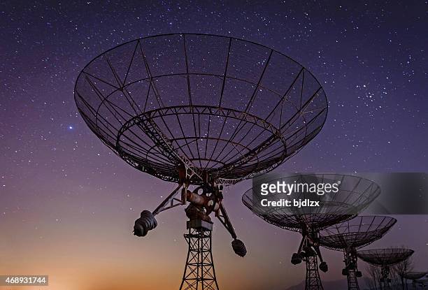 low angled view of radio telescopes with milky way in sky - globe navigational equipment stock pictures, royalty-free photos & images