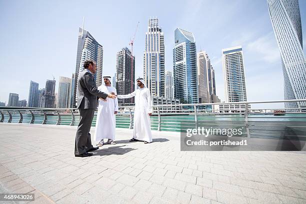 a trio of businessmen standing in front of the city skyline - dubai business stock pictures, royalty-free photos & images