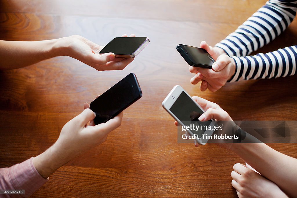 4 friends sharing on smart phones.