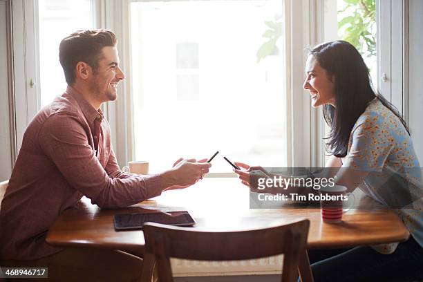 man and woman using smart phones at table. - phone on table stock pictures, royalty-free photos & images