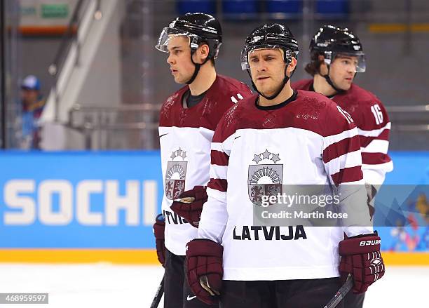 Martins Karsums, Kristaps Sotnieks and Kaspars Daugavins of Latvia look on at the start of the Men's Ice Hockey Preliminary Round Group C game...