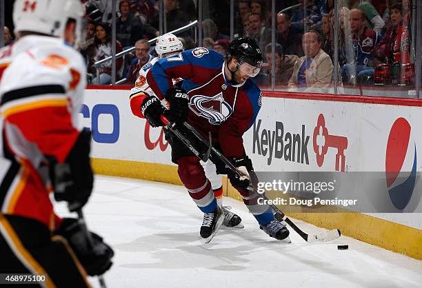 Brad Stuart of the Colorado Avalanche contols the puck against Sean Monahan of the Calgary Flames at Pepsi Center on March 14, 2015 in Denver,...