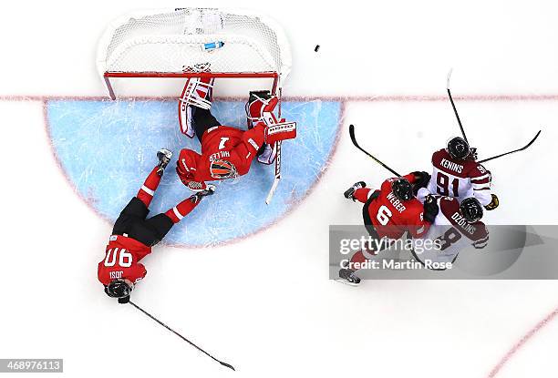 Jonas Hiller of Switzerland makes a save against Sandis Ozolins and Ronalds Kenins of Latvia as Roman Josi and Yannick Weber defend in the third...